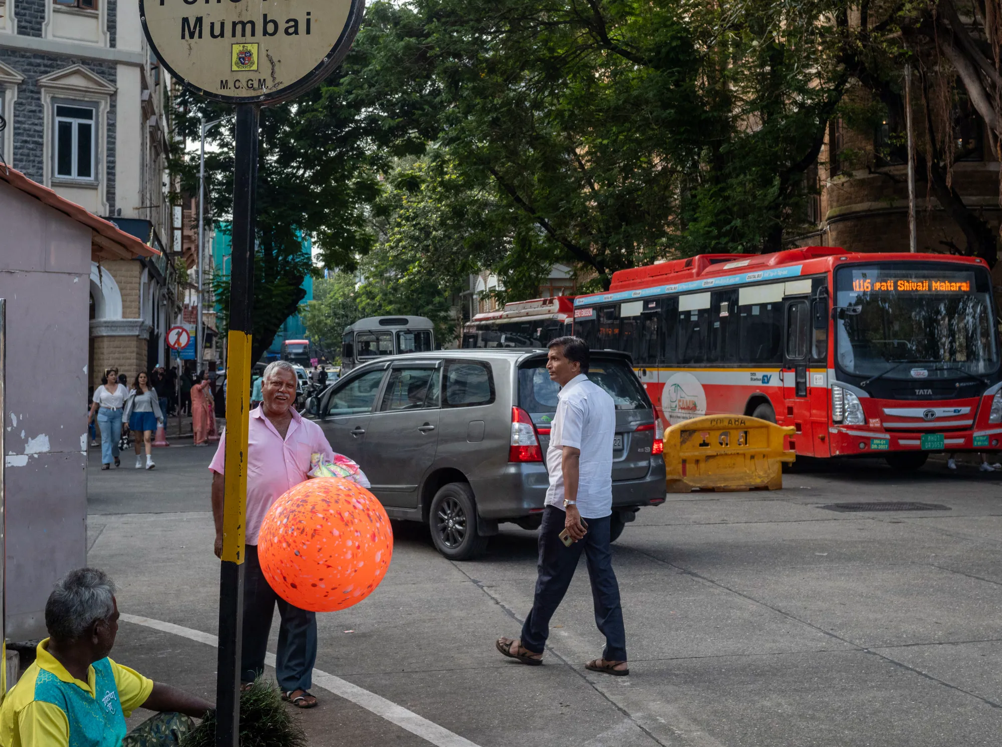 Street scene in Mumbai with pedestrians, cars, and city buses.