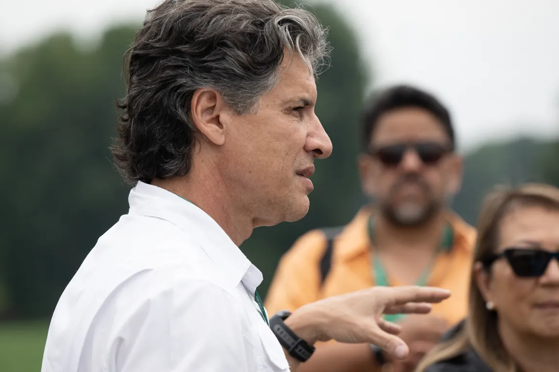 A man speaks to a group outdoors.