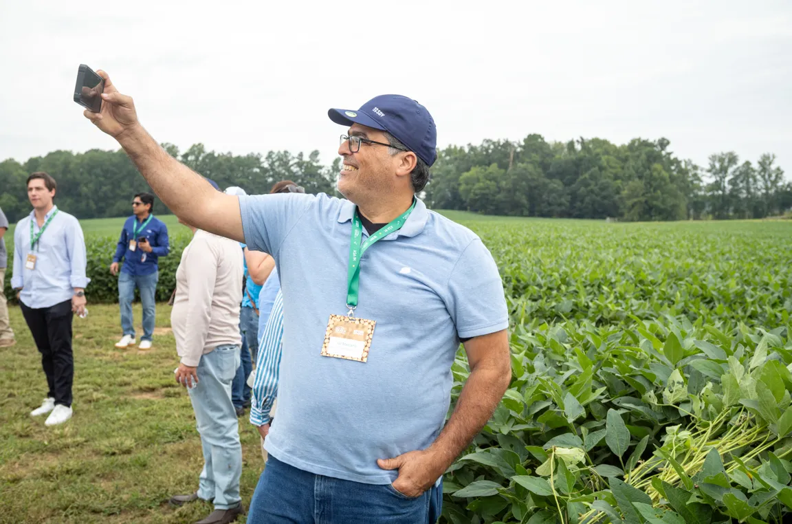 A man takes a photo near a field.