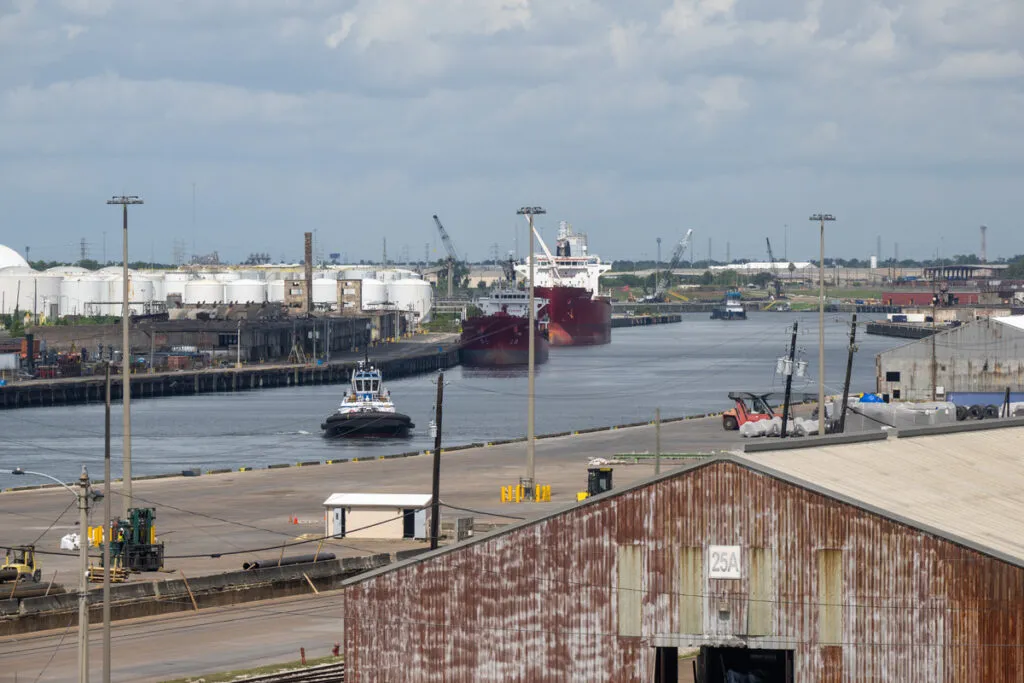 Industrial port with cargo ships, storage tanks and waterfront facilities.
