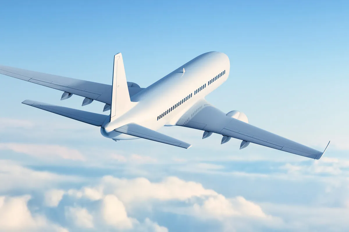 Commercial passenger airplane flying above the clouds against a clear blue sky.