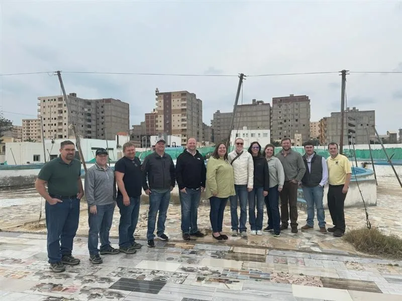 Group of people posing together outdoors during a visit in Egypt, with city buildings in the background.