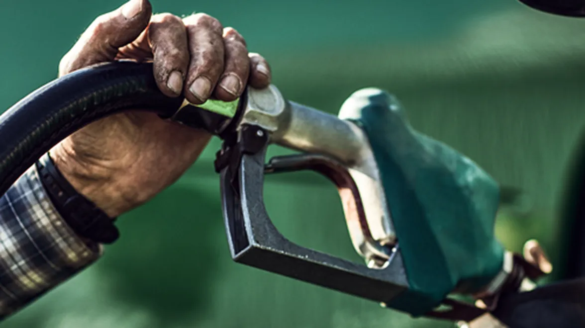 Hand fueling a vehicle with a biodiesel pump nozzle representing soybean oil’s role in biofuel.
