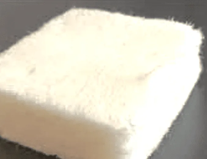 A small white foam-like block with a soft, fibrous texture.