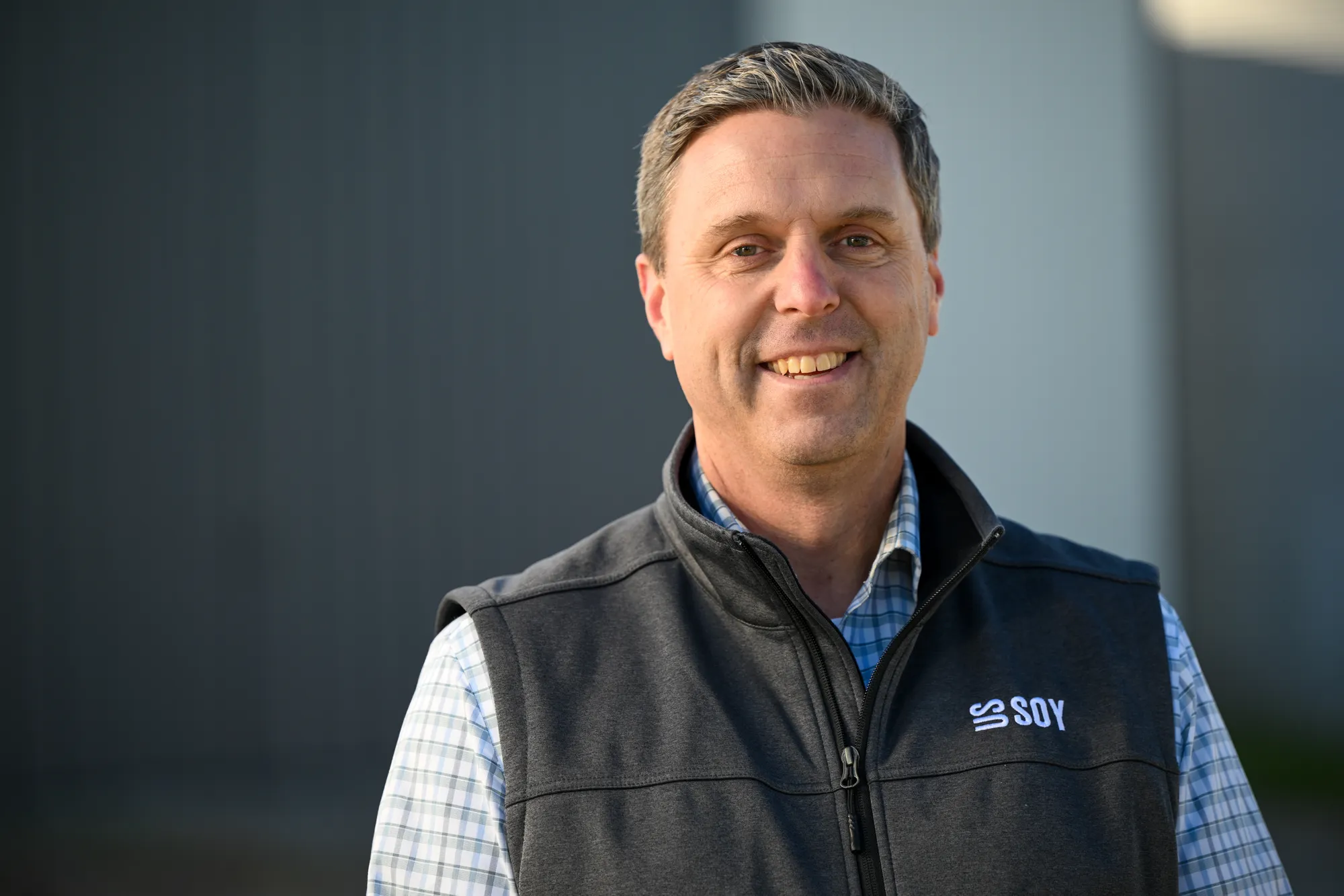 Farmer-leader standing in front of a blurred building.