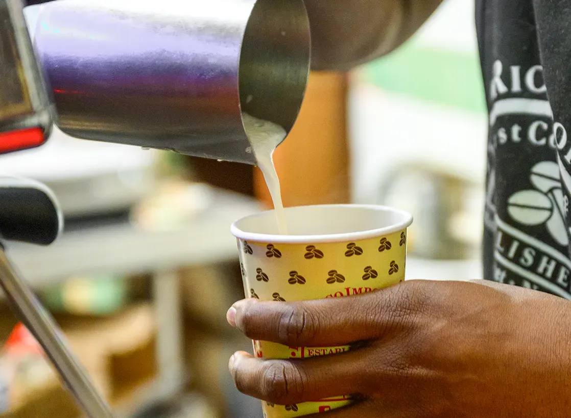 Image of person pouring soy milk into a coffee cup. 