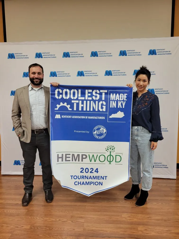 Two people holding a banner announcing HempWood as the 2024 ‘Coolest Thing Made in Kentucky’ tournament champion.