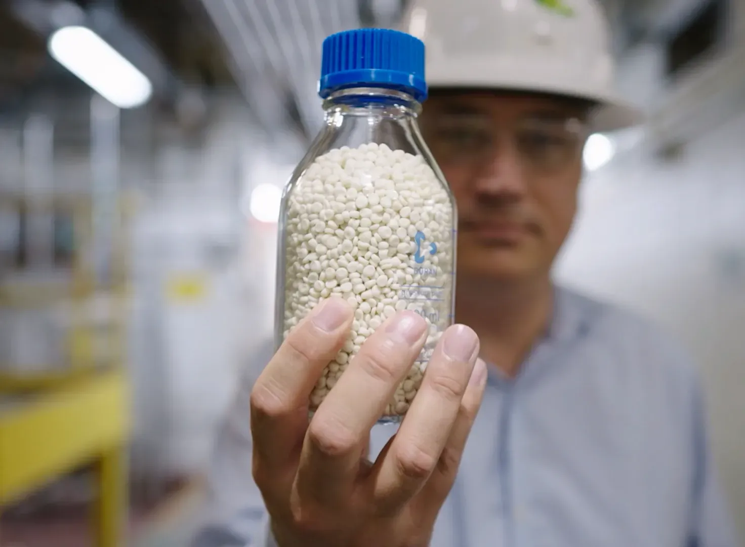 Man holding bottle of bio plastic pellets made from soybeans. 