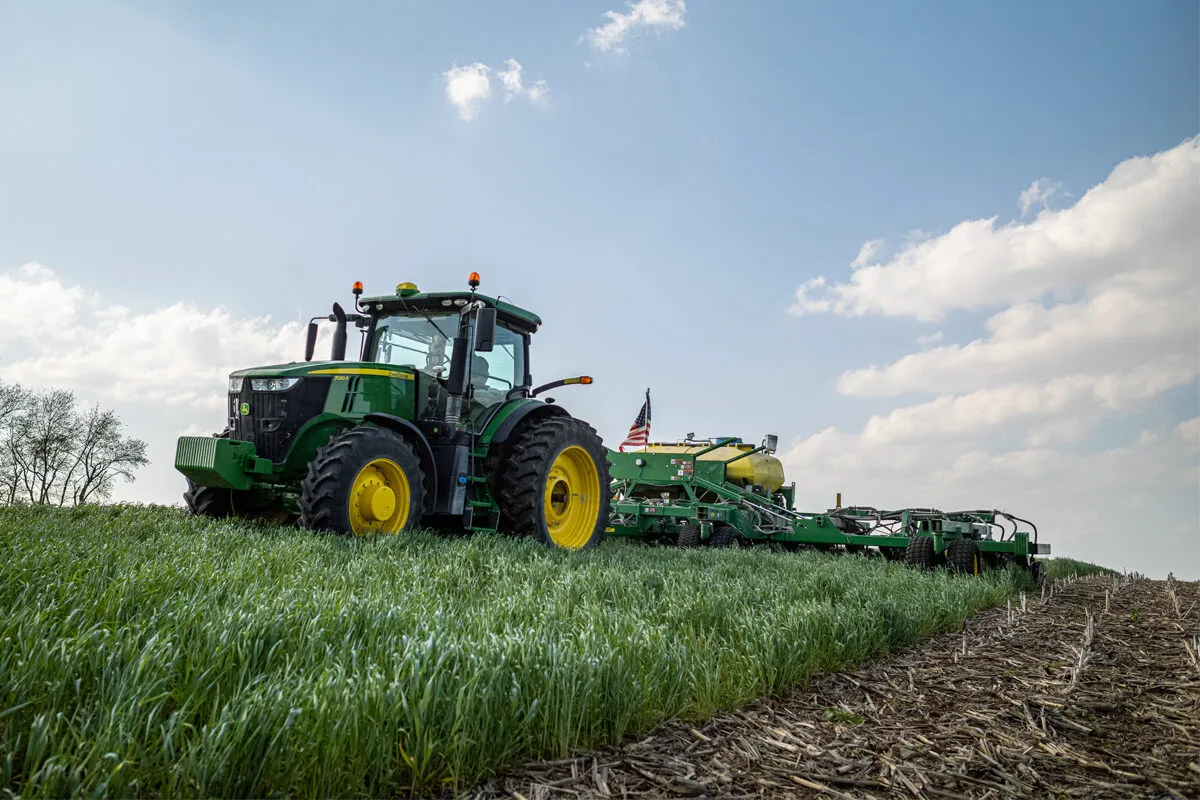 A tractor and planter move through a field of cover crops and crop residue as soybeans are planted.