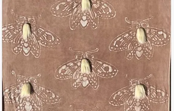 A patterned textile featuring repeated moth illustrations, each accented with a small cream-colored threaded tassel.