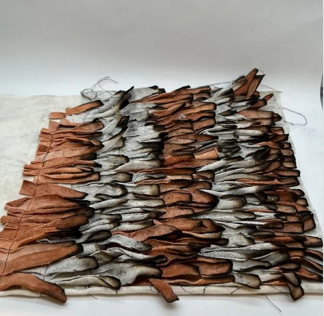 A textured upholstery fabric sample made of layered, curled textile strips in shades of brown, tan, and gray.