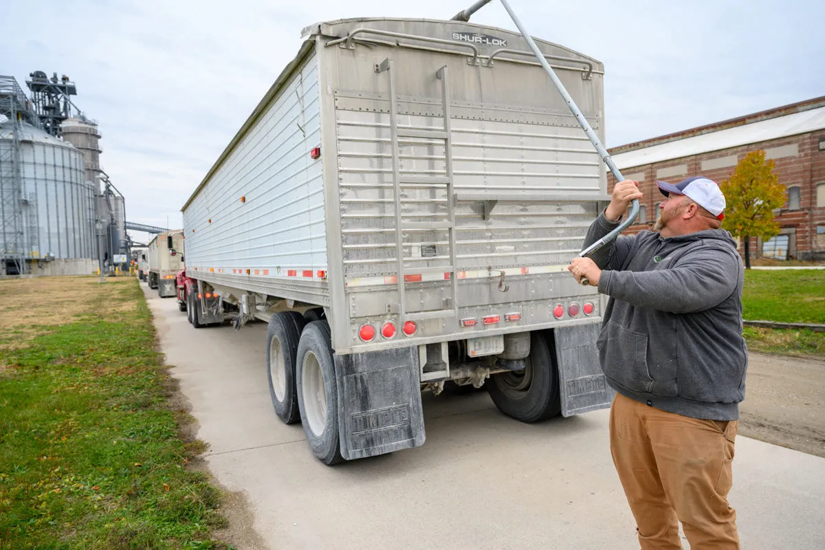 Farmer operates the tarp system on a grain trailer at a soybean processing facility.