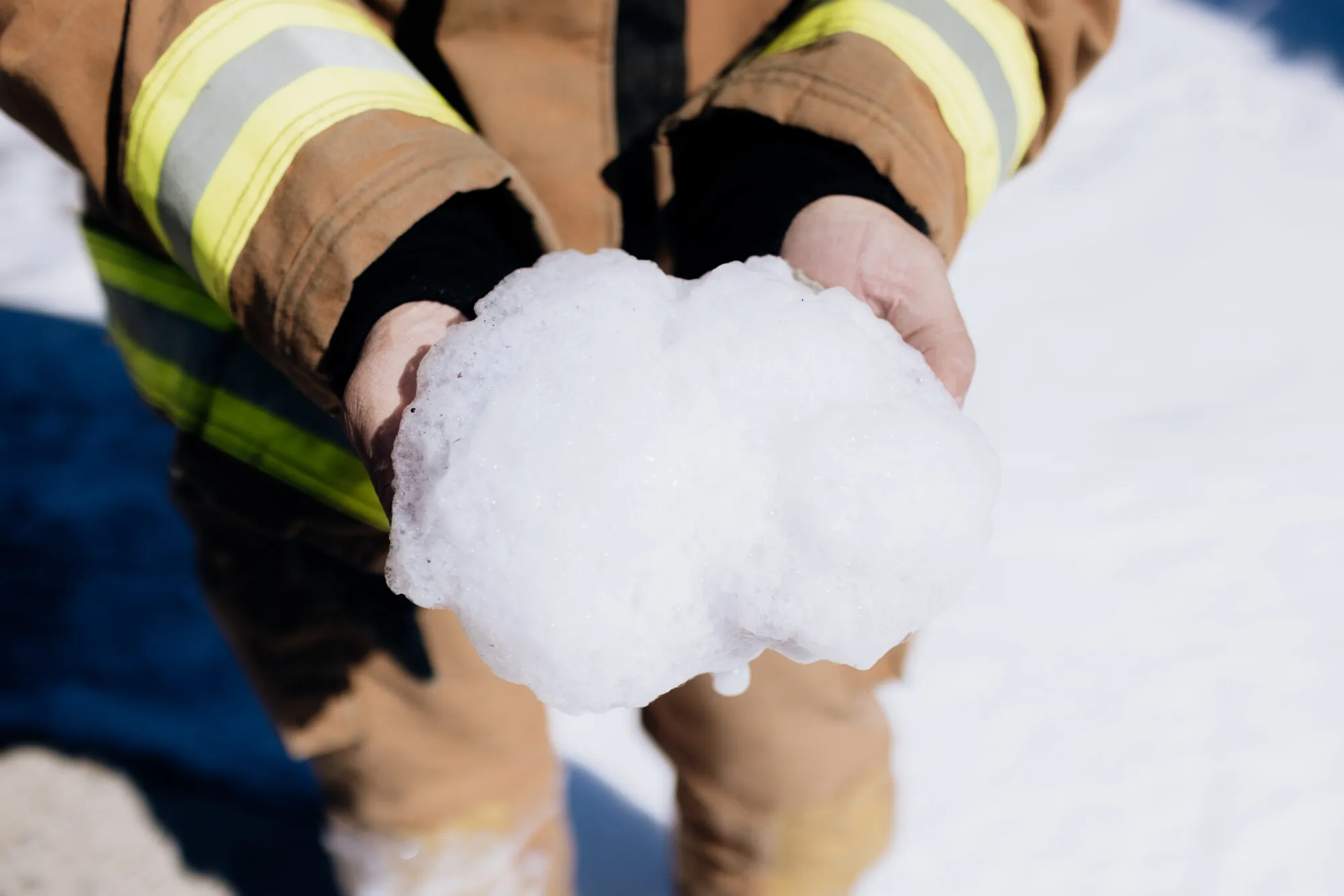 Close-up of a person in reflective workwear holding a handful of soy foam.