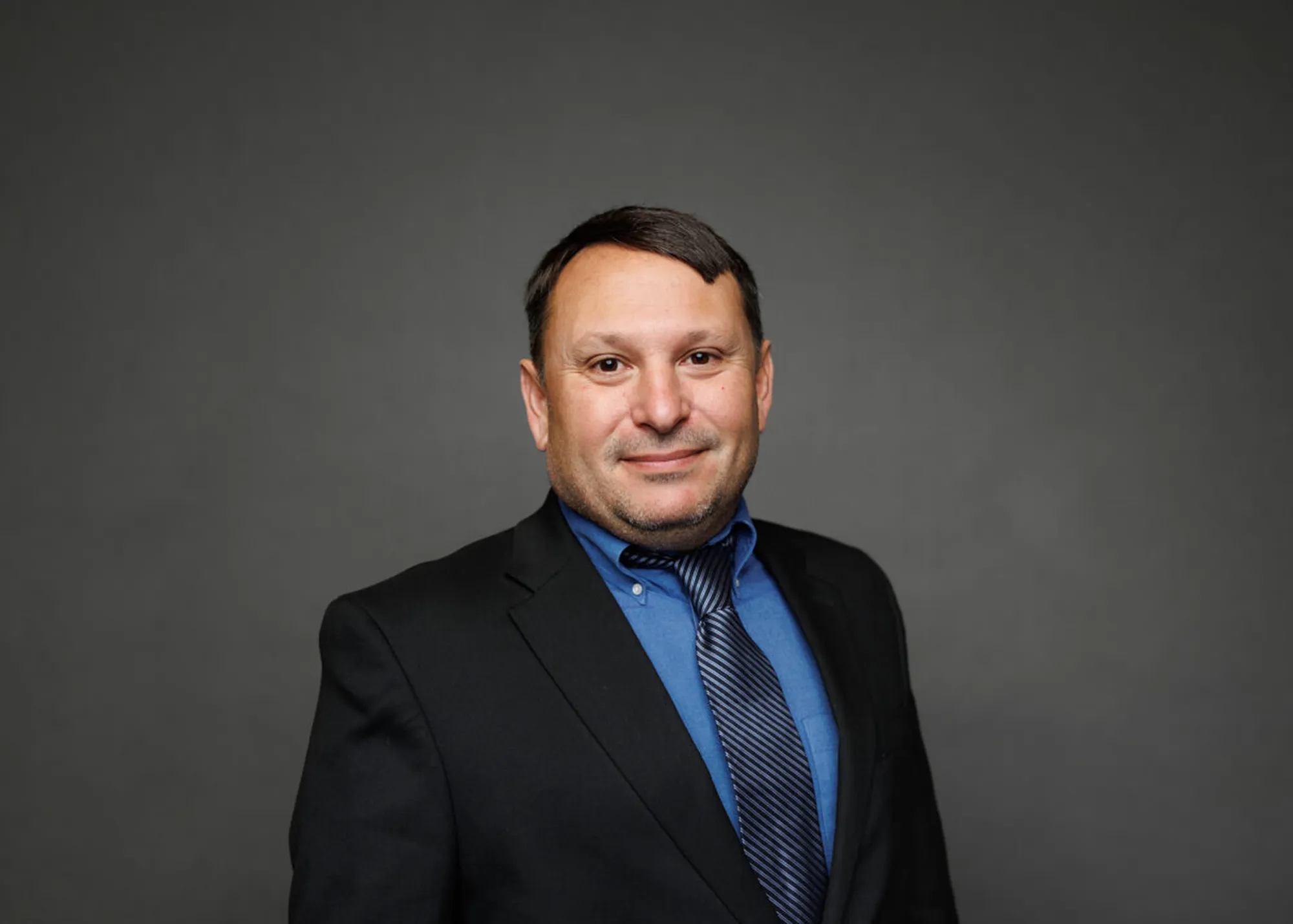 Professional headshot of a farmer-leader against a gray background.