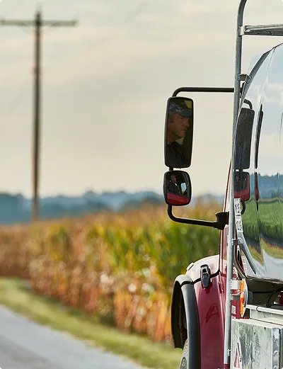 Truck driving down country road by field