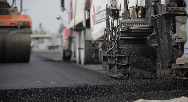 Road repair crew applying soy-based asphalt rejuvenators to protect infrastructure.