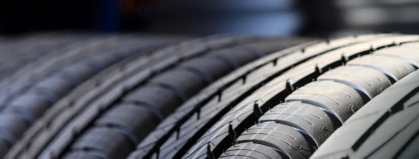 Close-up of several black vehicle tires showing detailed tread patterns, with the nearest tire sharply in focus.